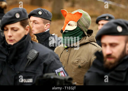 26 mars 2019, Berlin, Düsseldorf : Un homme dans un déguisement va à un véhicule d'urgence avec les policiers pour vérifier ses données personnelles. Au cours de l'opération policière pour une suspicion d'excréments dans le lanceur de Hambach forêt, une personne en cordée vers le bas d'une maison de l'arbre. Un porte-parole de la police a déclaré mardi qu'elle avait été prise d'une voiture de police pour déterminer ses coordonnées personnelles. Photo : David Young/dpa Banque D'Images