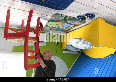 Wolgast, Allemagne. Mar 26, 2019. Richard m'appuie une chaise dans une chambre à l'envers sur l'île d'Usedom. Les entrepreneurs polonais de Szczecin (Szczecin) voir l'appartement, dans lequel tous les objets sont placés à l'envers afin de donner aux visiteurs une vue particulière de la vie quotidienne. La chambre, qui a ouvert ses portes en 2008, est d'être rénové par le week-end de la nouvelle saison. Personne ne devrait vivre dans la chambre - il est destiné à des fins de musée et d'une partie du projet "Le monde est à l'envers'. Credit : Stefan Sauer/dpa-Zentralbild/dpa/Alamy Live News Banque D'Images