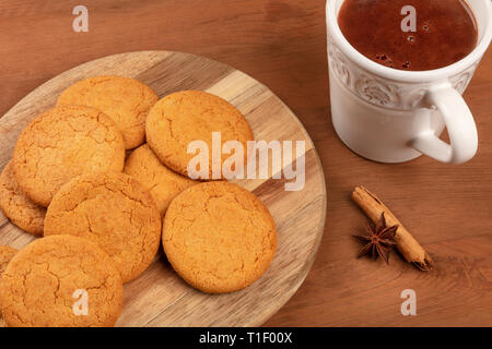 Un gros plan des cookies au gingembre avec une tasse de chocolat chaud, un bâton de cannelle, et une étoile d'anis sur un fond rustique en bois foncé Banque D'Images