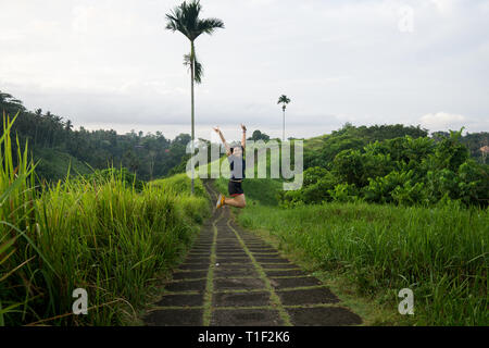 Happy girl saute au milieu d'une piste de jogging au Ubud Bali Banque D'Images