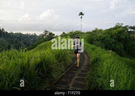 Happy girl saute au milieu d'une piste de jogging au Ubud Bali Banque D'Images