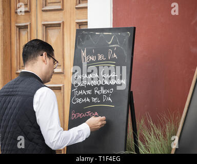 Waiter writing menu del dia, [menu du jour] le tableau situé à l'extérieur restaurant à Vegueta, Las Palmas, Gran Canaria, Îles Canaries, Espagne Banque D'Images