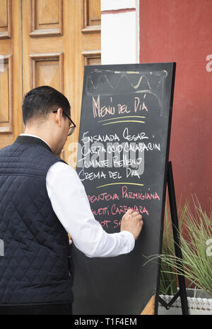 Waiter writing menu del dia, [menu du jour] le tableau situé à l'extérieur restaurant à Vegueta, Las Palmas, Gran Canaria, Îles Canaries, Espagne Banque D'Images