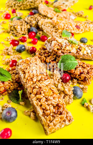 Barres de céréales avec les noix, les fruits et les baies, fond jaune lumineux top view copy space Banque D'Images