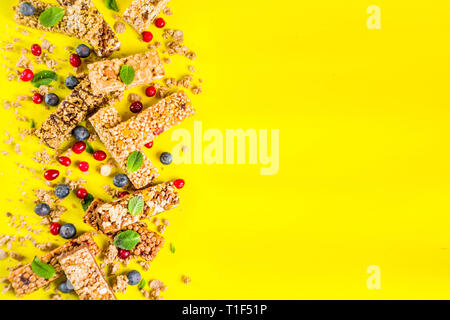 Barres de céréales avec les noix, les fruits et les baies, fond jaune lumineux top view copy space Banque D'Images