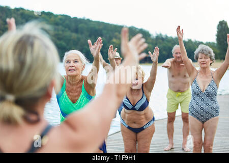 Groupe de femmes âgées faisant retour formation ensemble au bord du lac en été Banque D'Images