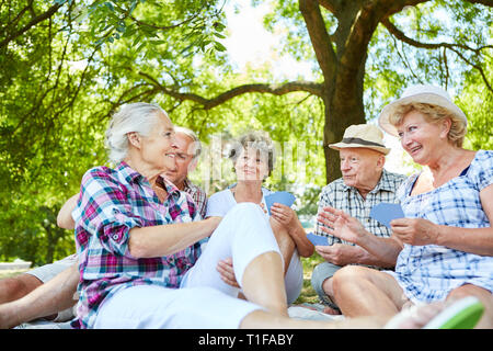 Groupe de personnes âgées amis jouer aux cartes ensemble dans l'été dans le jardin Banque D'Images