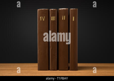 Volumes de livres en cuir brown couvre sur table en bois isolé sur black Banque D'Images