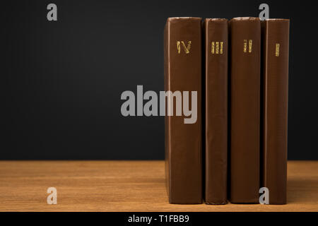 Volumes de livres vintage en cuir brown couvre sur table en bois isolé sur black Banque D'Images