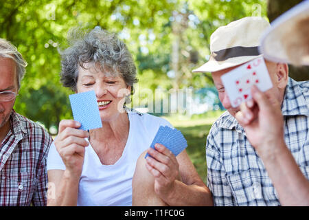 Les personnes âgées jouent aux cartes ensemble dans le parc pour la détente ou la compétition Banque D'Images