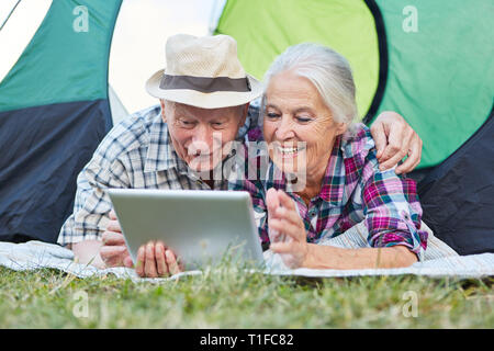 Senior couple on camping locations en tente avec un ordinateur tablette Banque D'Images