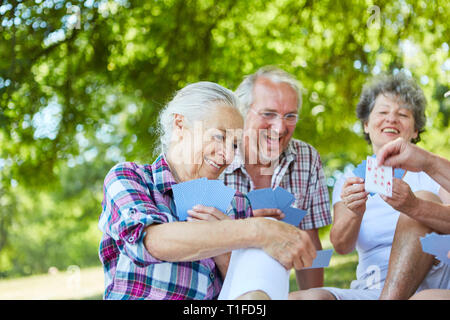 Groupe d'aînés s'amuse tandis que les cartes à jouer ensemble dans le jardin de la maison de retraite Banque D'Images