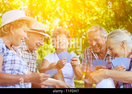 Groupe d'aînés heureux ensemble tout en jouant aux cartes en été Banque D'Images