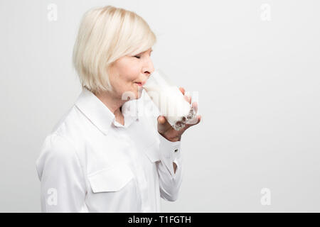 Vue de coupe blonde woman standing et de boire une tasse de lait biologique. Elle est en cela. Isolé sur fond blanc. Banque D'Images