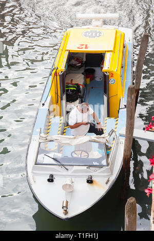 Ambulance vénitienne en attente dans un canal de collecte d'un patient, Venise, Vénétie, Italie, de haut en bas avec les membres du personnel dans le bateau et vue d'i Banque D'Images