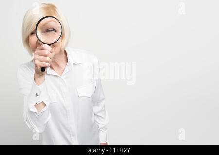 Portrait de vieille femme suspecte en blouse blanche regarde droit devant lui à travers la lecture en verre. Elle a l'air étrange. Couper la vue. Isolated on white Banque D'Images