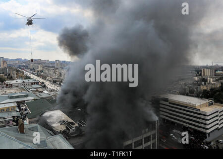 Baku, Azerbaïdjan. Mar 26, 2019. Un hélicoptère s'apprête à déposer de l'eau sur un incendie au marché du Diqlas à Bakou, Azerbaïdjan, le Mardi, Mars 26, 2019. Un grand incendie s'est déclaré ce matin dans le centre commercial "iglas' dans le village de 8 kilomètre à Bakou. Brûler les étages supérieurs de l'édifice de cinq étages. Credit : Aziz Karimov/Pacific Press/Alamy Live News Banque D'Images