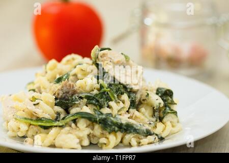 Tas de pâtes aux épinards à la crème et de la viande de poulet, tomate rouge et gousses d'ail en arrière-plan Banque D'Images