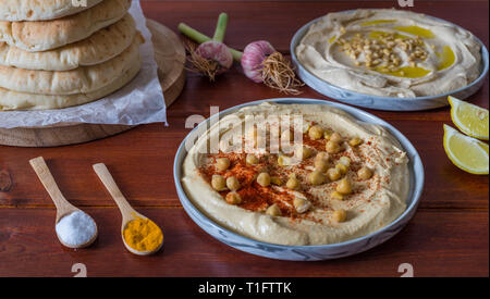 Plaques d'humus avec pain pita en bois sur fond rouge Banque D'Images