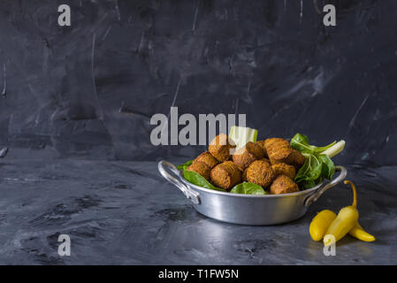 Boules de falafel servi dans la plaque avec feuilles vertes sur fond noir en bois Banque D'Images