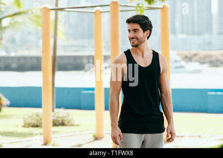 Beau jeune homme de la formation et de l'élaboration dans parc. Bel athlète hispanique et permanent à la recherche à l'appareil photo après programme de conditionnement physique. Portrait de Lati Banque D'Images