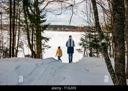 Deux jeunes filles à pied à travers la forêt d'hiver à un lac gelé. Un merveilleux changement de saison, l'arrivée du printemps, tout vient à la vie avec la FIRS Banque D'Images