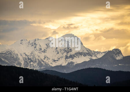 Vue du Lac de Wörthersee au coucher du soleil sur la montagne couverte de neige sur un sprint Mittagskogel nuageux jour en Carinthie en Autriche Banque D'Images