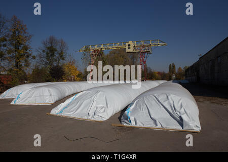 Le thème est l'industrie et agraire. La moisson est stocké dans de grands, imperméables, étanches sacs blancs à l'air libre à l'extérieur de la ferme. Banque D'Images