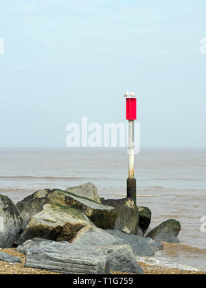 Un épi de rock sur Horsey, plage de sable de la pièges Norfolk longshore drift.Le pylône et la plaque d'avertissement rouge sont pour la protection dans des bateaux côtiers. Banque D'Images