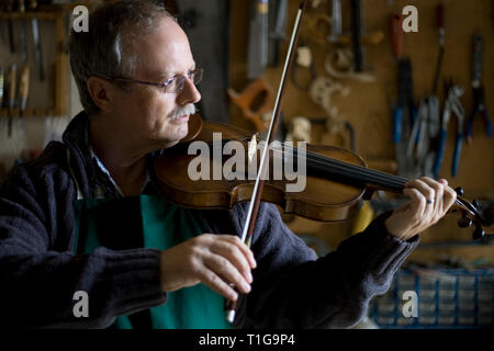 Andrew Hutchinson à l'essai un Violin and Bow dont il vient de terminer la réparation et restauration dans son atelier à Hoylake, Wirral, nord-ouest de l'Angleterre. M. Hutchinson formés à l'école de lutherie de Newark et créé la boutique de violon en 1982, où il a mené d'importantes réparations sur environ 300 violons chaque année, en plus d'effectuer de petits réglages et mise au point sur une autre 800. Banque D'Images