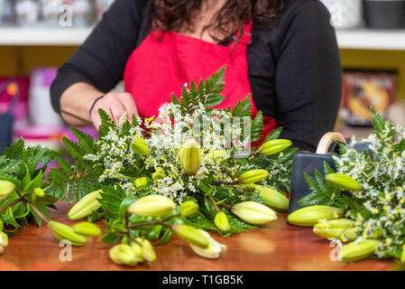 Fleuriste femme Portant tablier, debout au comptoir faire bouquet pour client au magasin de fleur . Banque D'Images