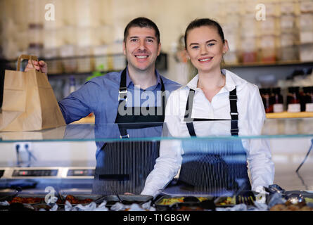 Jeune homme et femme debout derrière le comptoir d'un restaurant. Derrière la cuisine Banque D'Images