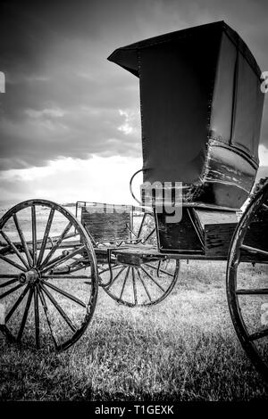 Un mystérieux et lonesome vue sur un style ancien siège deux surrey ou buggy, prêt pour l'accrochage, assis dans la praire aux ETATS UNIS en noir et blanc Banque D'Images