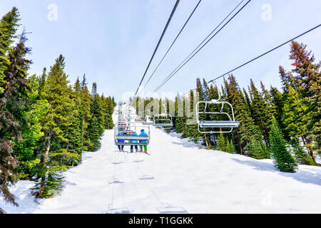 Les skieurs non identifiables sur télésiège remontant une pente de ski dans la montagne enneigée (éventail des Rocheuses canadiennes. Banque D'Images