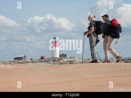 HÅLLÖ 20170817 certains qui marche sur les rochers de l'île de Hållö juste en dehors de Smögen. Hållö phare en arrière-plan. Jeppe Photo Gustafsson Banque D'Images