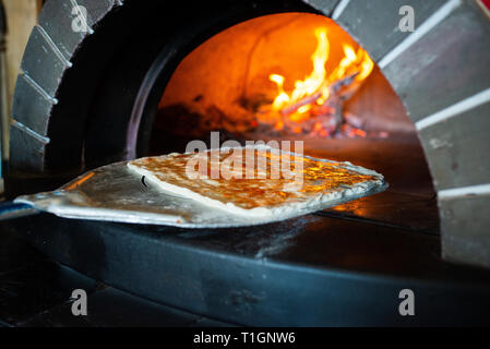 Pizza italien de style romain sur peel base spade sur le point d'être mis dans un four à bois pour la cuisson dans une trattoria/restaurant/pizzeria Banque D'Images