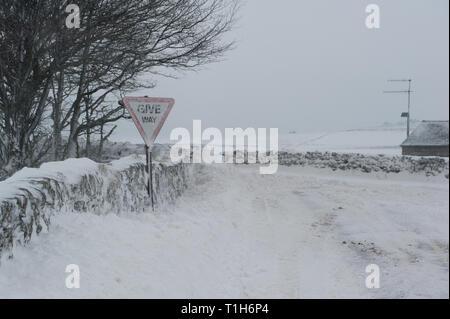 La neige a couvert la jonction de route en zone rurale, à céder le passage panneau d'avertissement de neige Banque D'Images