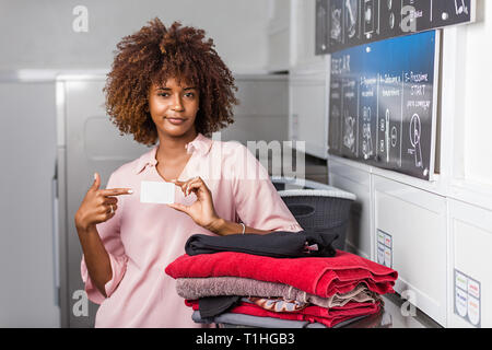 Young black African American Woman holding une carte d'abonnement de blanchisserie Banque D'Images