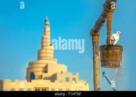 Pigeon boit de l'eau au vieux puits fontaine, établissement emblématique de la milieu de Souq Waqif à Doha, Qatar, du centre-ville. Moyen-orient, Péninsule Arabique Banque D'Images