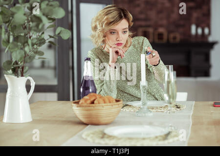 Navré copine assise à table avec l'alcool et des croissants seul Banque D'Images