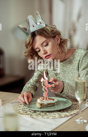 Woman wearing gold ring boucles d'allumer une bougie sur le gâteau Banque D'Images