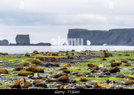 Vik, Islande paysage près de plage de sable noir avec horizon océan rock formation arch à Dyrholaey, sur la côte sud de l'Kirkjufjara avec moss rocks Banque D'Images