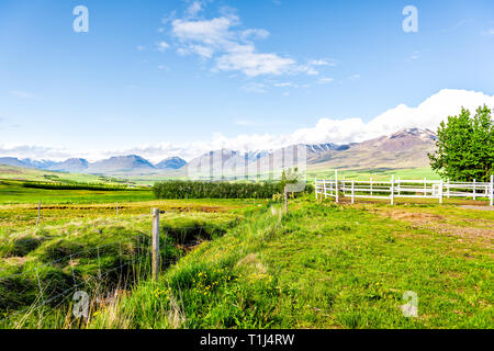 Vue des montagnes près de Akureyri avec ciel bleu et de pâturage clôture de ferme avec de l'herbe verte au cours de journée ensoleillée Banque D'Images