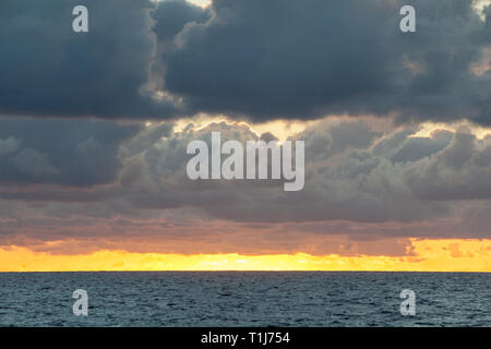 Un magnifique lever du soleil illumine les nuages au-dessus de la dérive sur la mer des Caraïbes. Banque D'Images