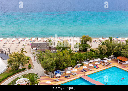 Belle vue sur piscine piscine avec eau bleu clair, chaises longues et parasol autour. Vue sur la mer avec des chiffres de touristes. Été Banque D'Images