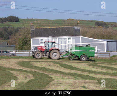 Castlehaven, West Cork, Irlande, le 27 mars 2019. Une autre belle journée de printemps et le beau temps a permis à un agriculteur local pour obtenir son premier de la saison de coupe de l'ensilage en balles et. Credit : aphperspective/Alamy Live News Banque D'Images