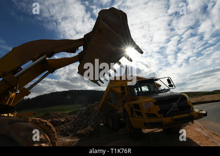 Wichmannshausen Sontra, Allemagne. Mar 27, 2019. Les véhicules de construction sont rétro-éclairées sur la construction du tunnel de l'emplacement de l'A44 dans le district Werra-Meißner. La construction du tunnel est d'être conduit à travers la montagne pour 95 millions d'euros sur près de 1,7 kilomètres. L'autoroute A44 dans le nord de la Hesse fait partie de l'unité allemande du projet de transport. Le gouvernement fédéral, le coût total à 1,7 milliards d'euros. La nouvelle autoroute est à 70 kilomètres de long et 20 kilomètres sont actuellement ouverts à la circulation. Credit : Uwe Zucchi/dpa/Alamy Live News Banque D'Images