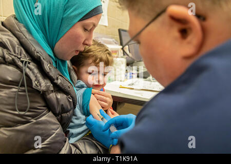 Southfield, Michigan, USA. Mar 27, 2019. Adam, Almahariq 2, obtient le vaccin ROR à la Oakland County Health Department pour le protéger contre une épidémie de rougeole. Vingt-deux cas de rougeole ont été confirmés dans la région depuis la visite d'un voyageur infecté provenant d'Israël. Almahariq Miranda tient son fils comme infirmière Jayne DeBoer-Rowse administre le coup. Crédit : Jim West/Alamy Live News Banque D'Images