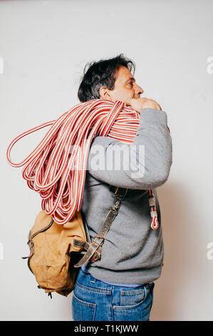 Sac à dos avec l'homme et la montagne de la corde, habillé décontracté, vu de profil, fond blanc Banque D'Images