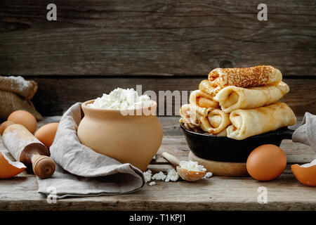 Poêle de crêpes au four, les ingrédients et ustensiles pour faire des crêpes sur table de cuisine en bois. Banque D'Images